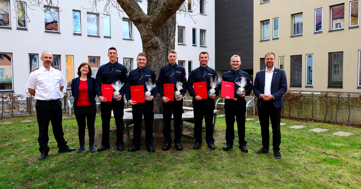 Der Oberbürgermeister der Stadt Jena Dr. Thomas Nitzsche (rechts), Nick Ludwig, stellvertretender Fachdienstleiter Feuerwehr (links), und Antonia Erdmann, Ausbildungskoordinatorin, gratulieren den neuen Feuerwehr-Anwärtern.